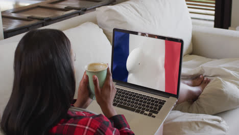 Mujer-Birracial-Mirando-Una-Computadora-Portátil-Con-Una-Pelota-De-Rugby-En-La-Bandera-De-Francia-En-La-Pantalla