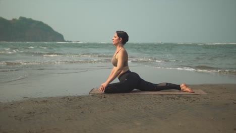 pigeon yoga position woman on a beach exercising asana, eka pada rajakapotasana outdoors