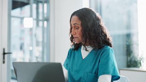 una doctora o enfermera sentada en un escritorio en una oficina, mirando pensativa.
