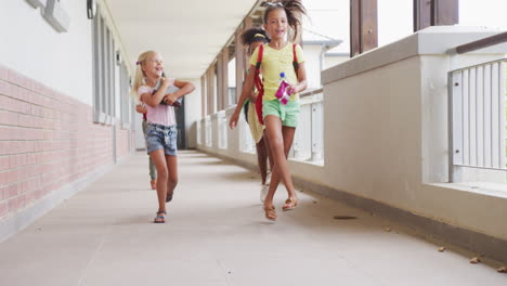 video of happy diverse girls running at school corridor and talking