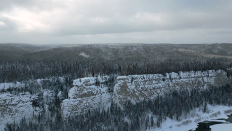 snowy winter landscape with frozen river and cliffs