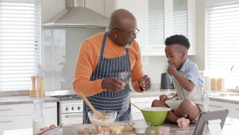 Happy-african-american-grandfather-and-grandson-baking-in-kitchen,-slow-motion