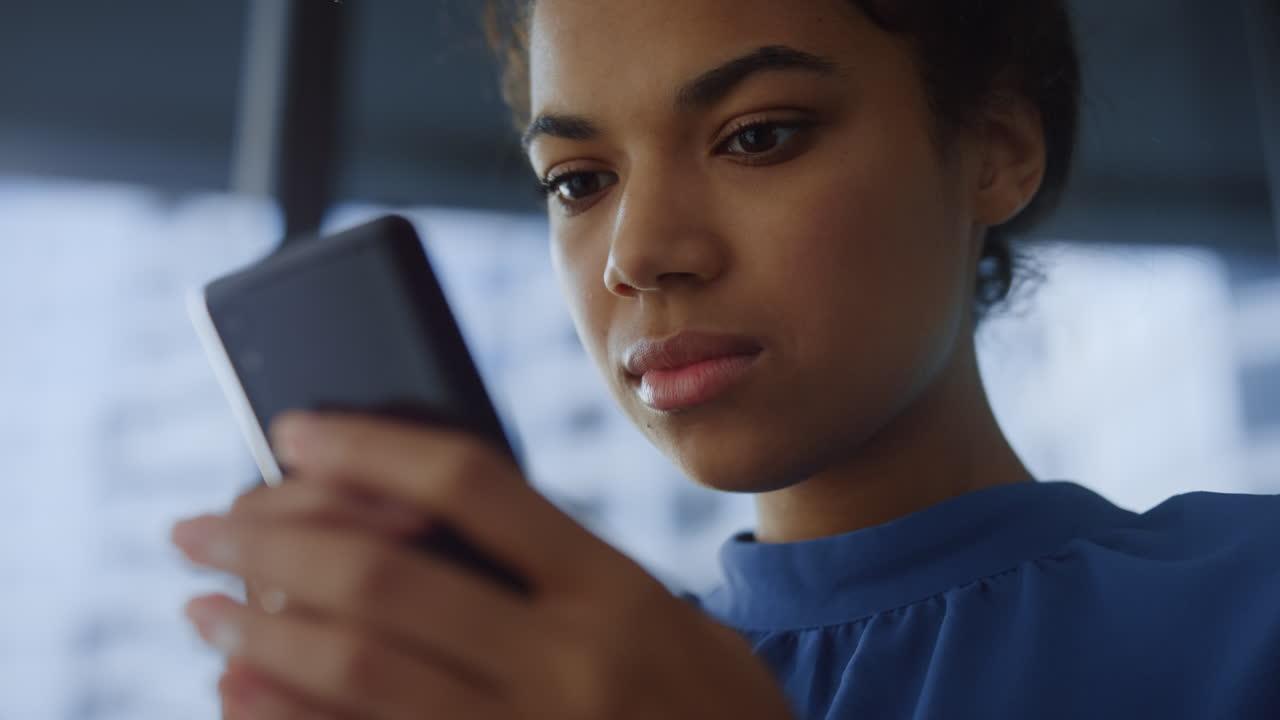 Donna d'affari pensierosa che naviga online con lo smartphone in ufficio.