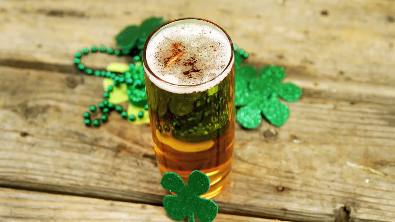 pinta de cerveza con decoración de tréboles en una mesa de madera para san patricio