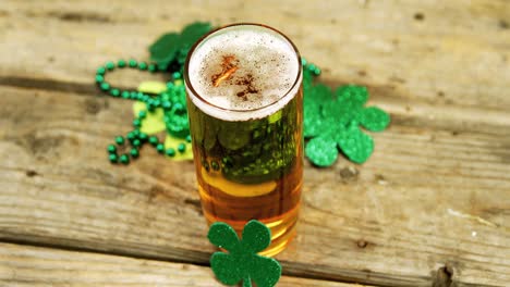 pint of beer with shamrocks decoration on wooden table for st patricks