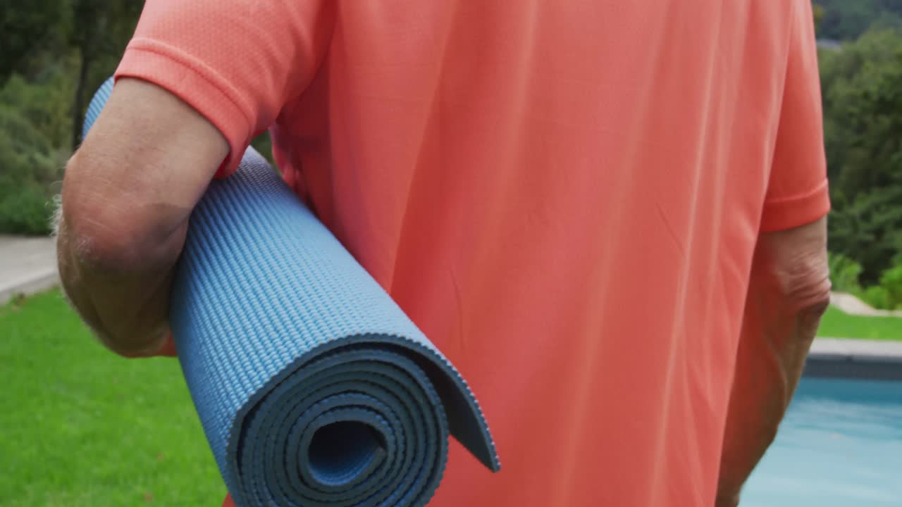 hombre mayor caminando con una alfombra de yoga