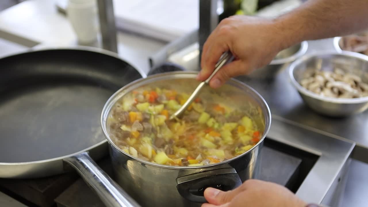 un chef agitando una olla de sopa de verduras vista lateral