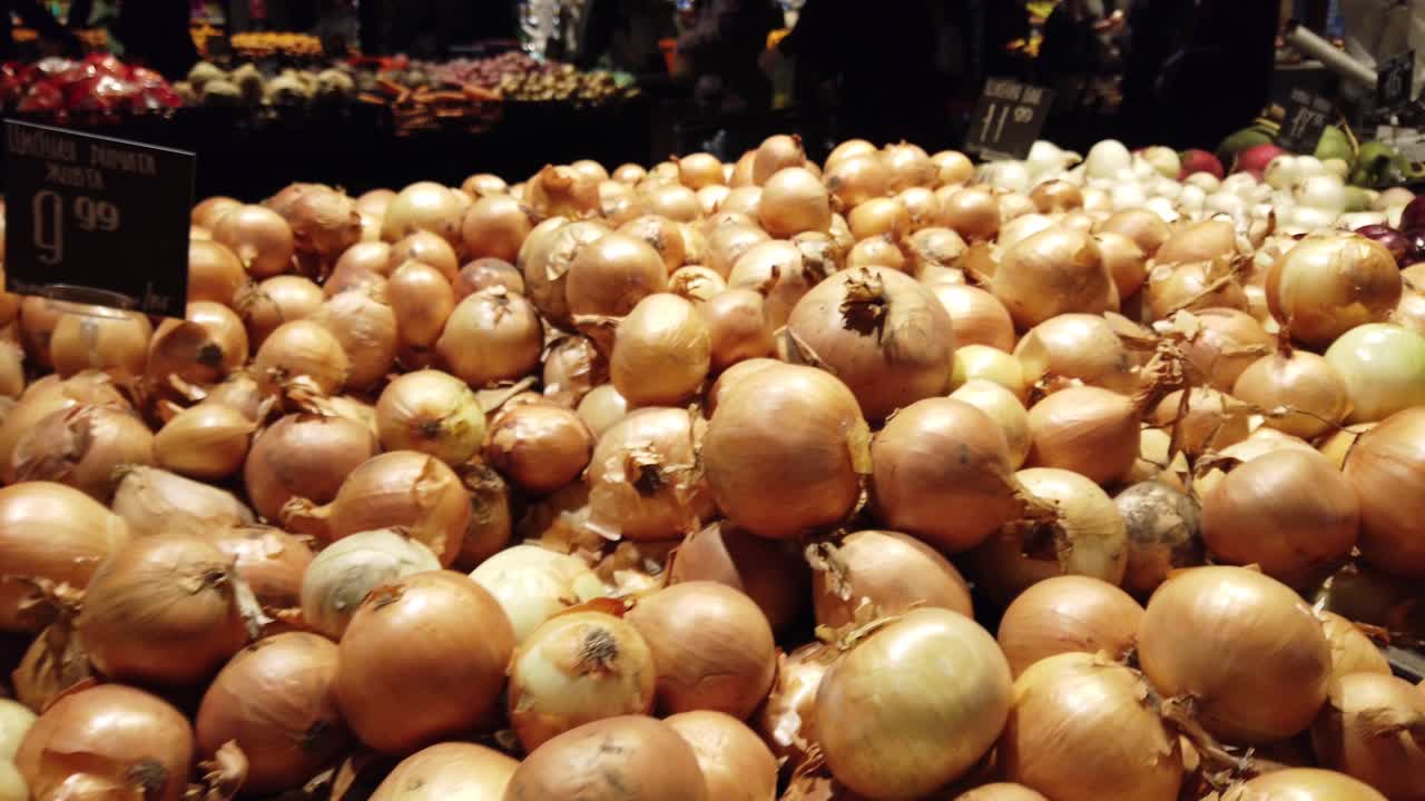 Cebolas no shopping. Compradores escolhem vegetais.