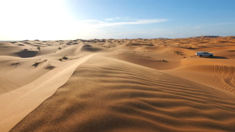 Pickup-truck-driving-offroad-through-the-windy-Sahara-in-Merzouga,-Morocco