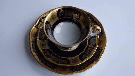 cup of tea. strong tea is poured from a teapot into a vintage cup inlaid with gold