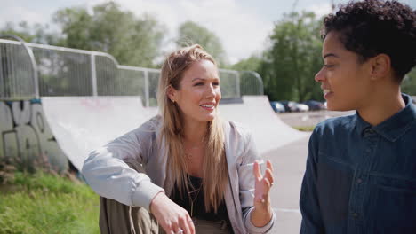 two female friends talking and laughing in urban skate park