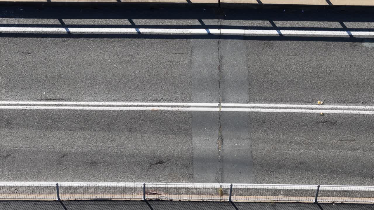 Overhead view of cars moving across a bridge under bright sunlight, highlighting urban transportation dynamics