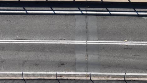 overhead view of cars moving across a bridge under bright sunlight, highlighting urban transportation dynamics