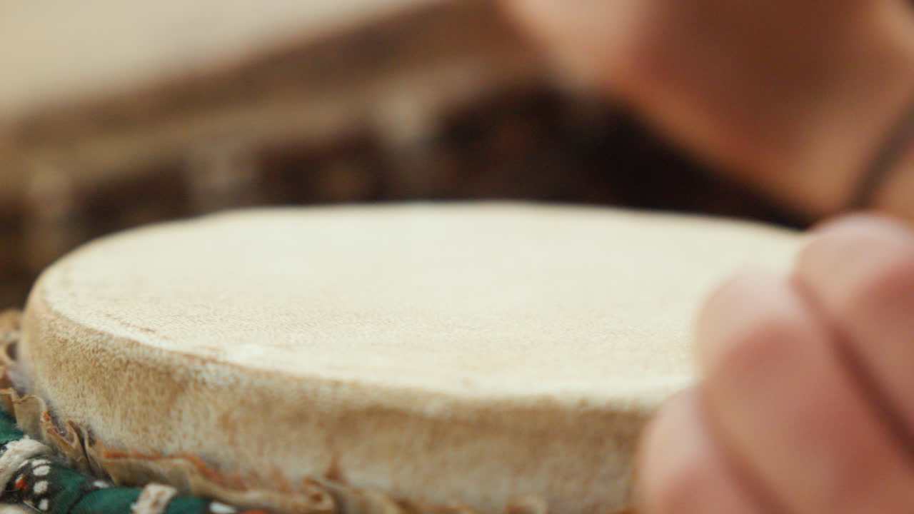 Close-up of a white woman's hands playing a bongo in slow motion, bathed in the soft light of the late afternoon