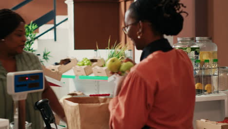 Merchant weighting fruits and veggies on scale for client
