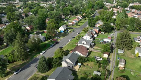 american single family houses along street during sunny day in virginia. aerial orbit wide shot. quiet suburb district of town. grass in garden and yards in summer