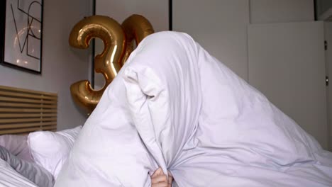 슬프고 지루한 여자가 침대에서 생일을 축하하고 있습니다.