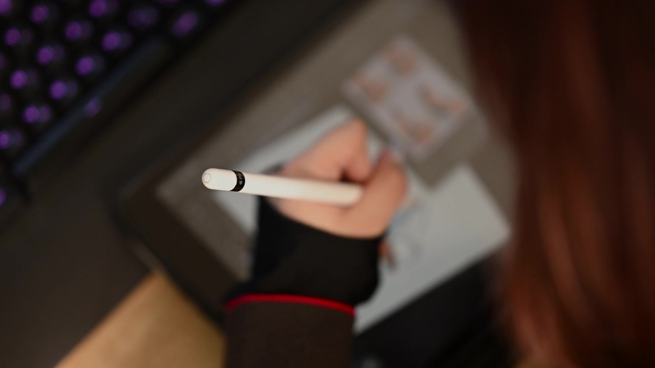 Detailní záběr na studenta/studentku používajícího/používající bílý stylus k nakreslení jednoduché skici postavy na digitálním kreslicím tabletu.