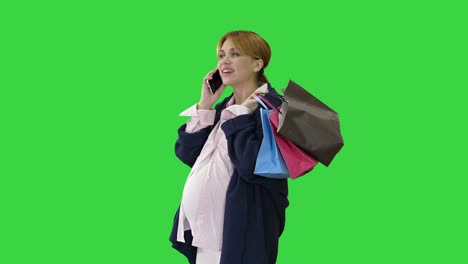 feliz mujer embarazada comprando y hablando por teléfono sosteniendo bolsas en una pantalla verde, llave de croma