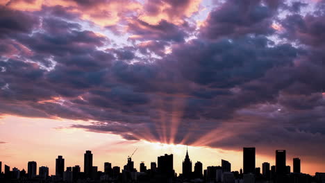 dramatic sunset or sunrise over city skyline with sun rays