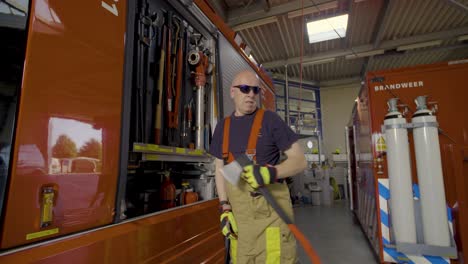 Firefighter-walking-towards-his-truck-and-retrieving-an-axe-from-the-fire-engine-slider-shot