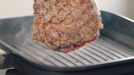 slow motion shot of turning a ribeye steak in a cast iron griddle pan