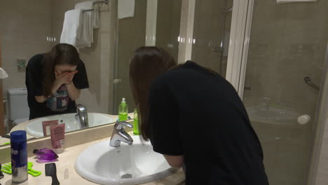 young woman washing hands in a hotel bathroom