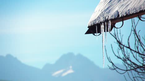 Eiszapfen,-Der-An-Einem-Sonnigen-Tag-Im-Winter-In-Den-Bergen-Von-Einem-Hüttendach-Hängt