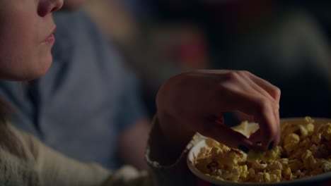 chica tomando palomitas de maíz de un cubo de papel a la boca. mujer comiendo palomitas de maíz en el cine