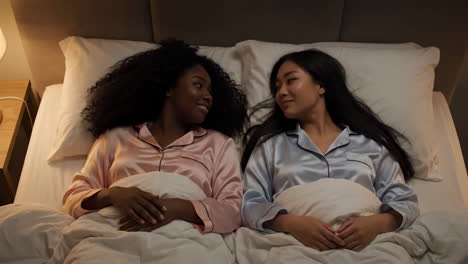 two women in pajamas lying in bed