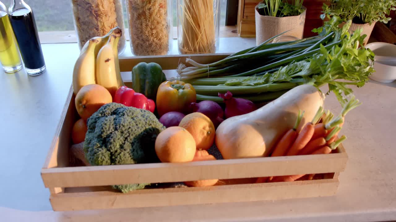 caja de verduras orgánicas y frascos de almacenamiento de alimentos en la encimera en la cocina soleada, cámara lenta