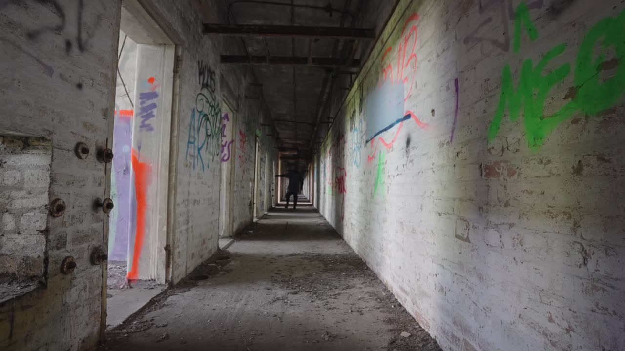 en la oscuridad una figura misteriosa desciende a lo largo de un corredor espeluznante, en cámara lenta.