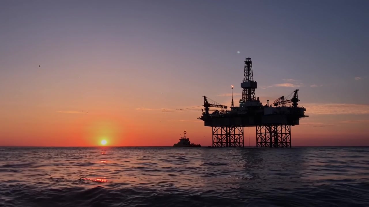 Piattaforma petrolifera offshore al tramonto con nave di supporto