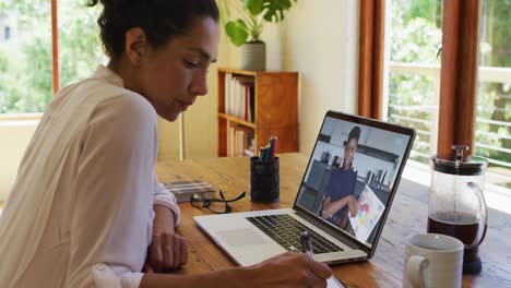 Mujer-Afroamericana-Tomando-Notas-Mientras-Realiza-Una-Videollamada-En-Una-Computadora-Portátil-En-Casa