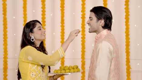 cute indian couple eating sweets on diwali