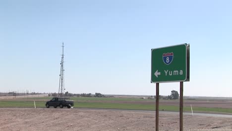 a truck drives by a road sign pointing to yuma