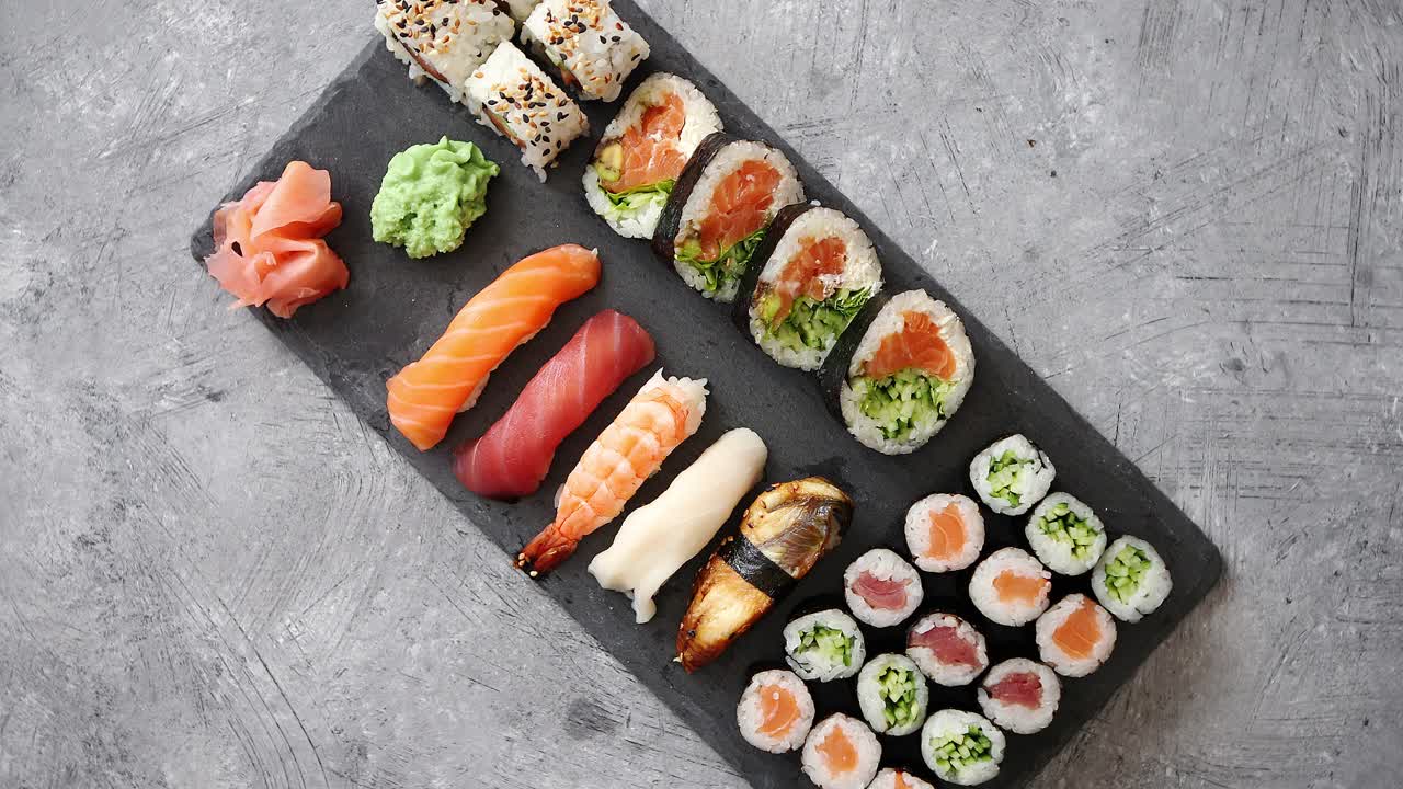 Sushi-sæt med laks og tunfisk serveret på en sort stenplade