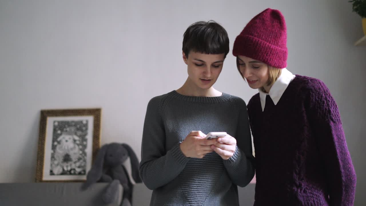 dos mujeres jóvenes mirando una foto en un teléfono móvil. amigas usando un teléfono inteligente