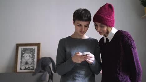 Two-young-woman-looking-photo-at-mobile-phone.-Female-friends-using-smart-phone