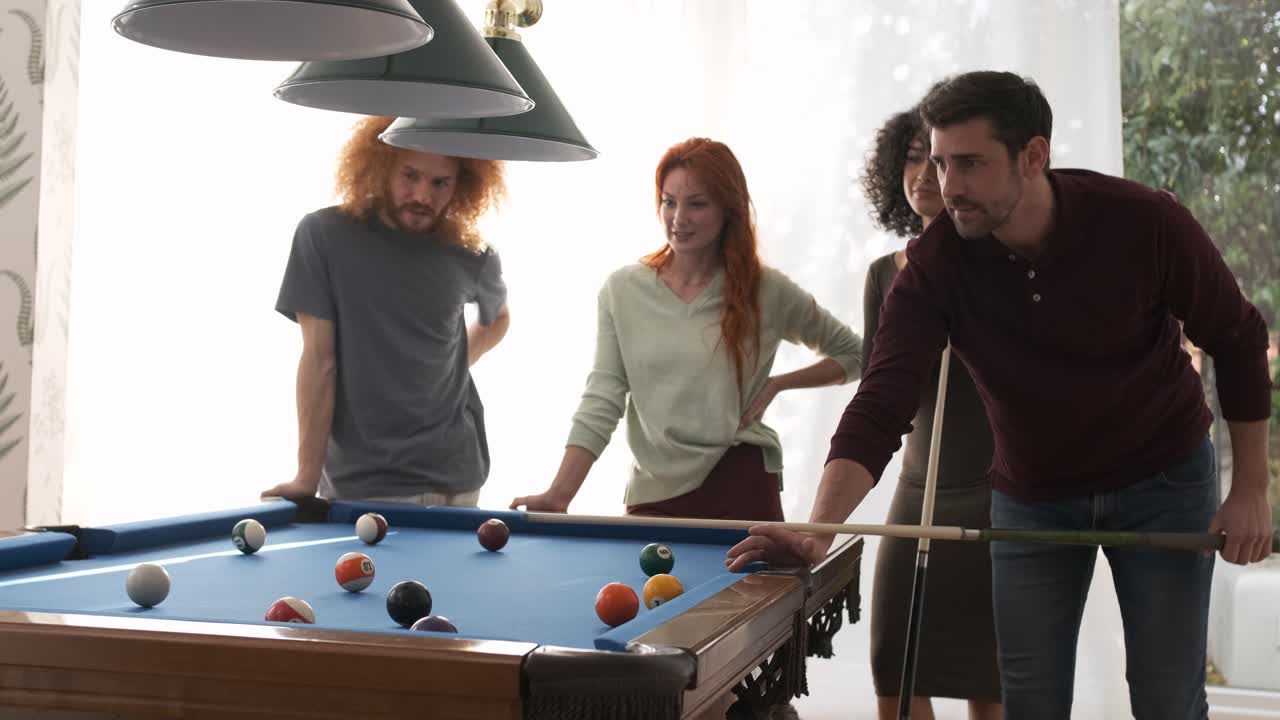 Friends watching man playing pool in game room