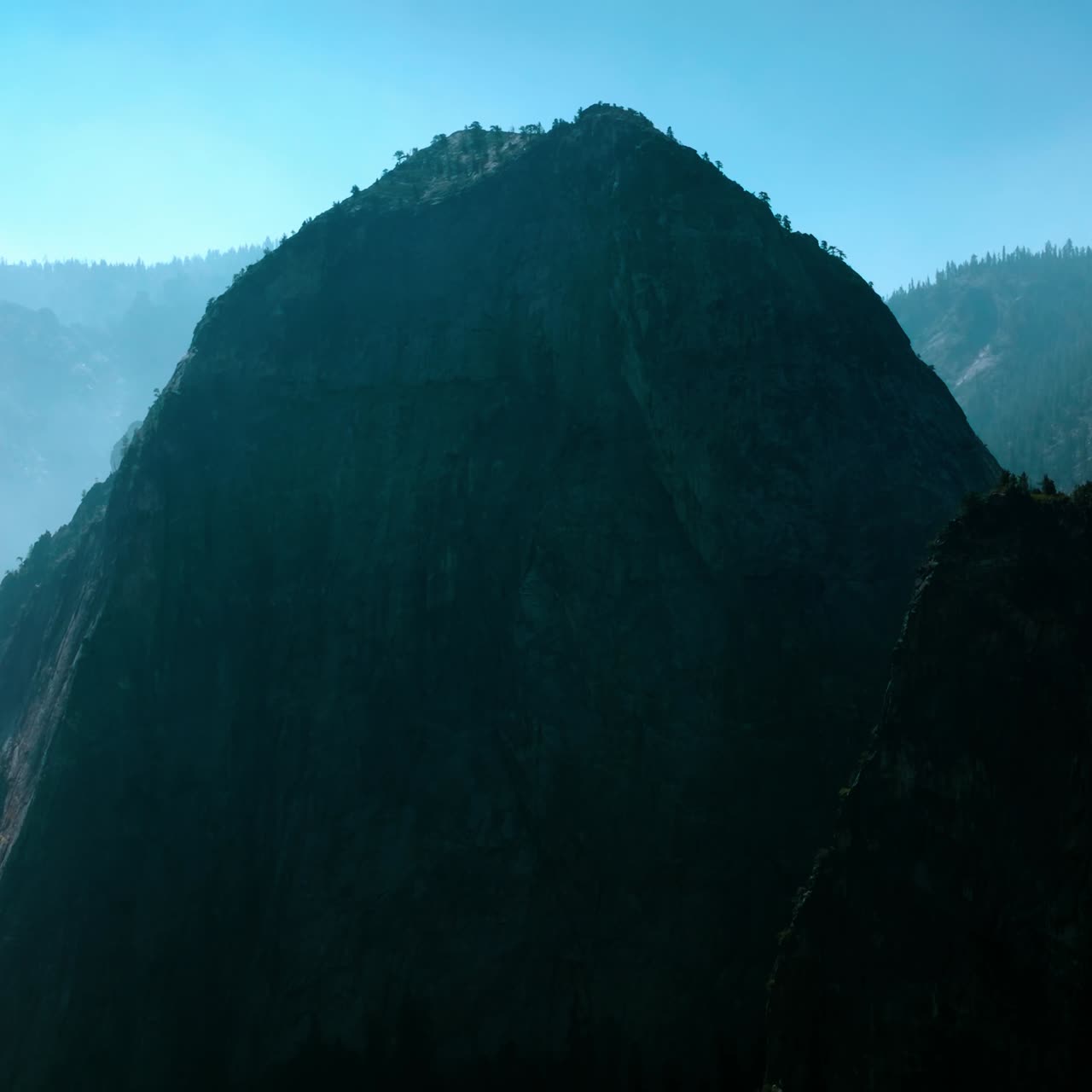 Two high rocks with some trees growing on top. Beautiful mountains in the fog in Yosemite National Park, United States