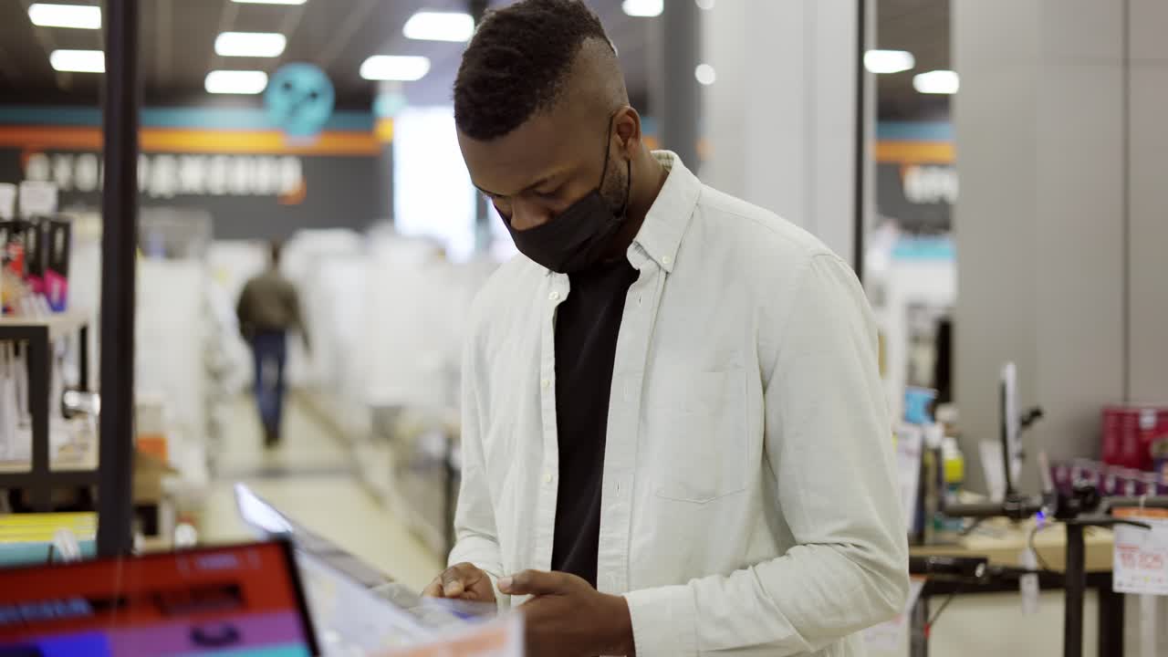 African American man is choosing a new mobile phone in a shot, checking how it works
