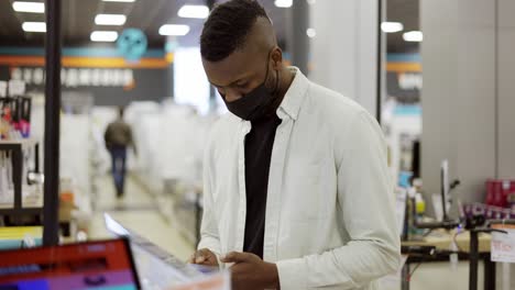 African-American-man-is-choosing-a-new-mobile-phone-in-a-shot,-checking-how-it-works