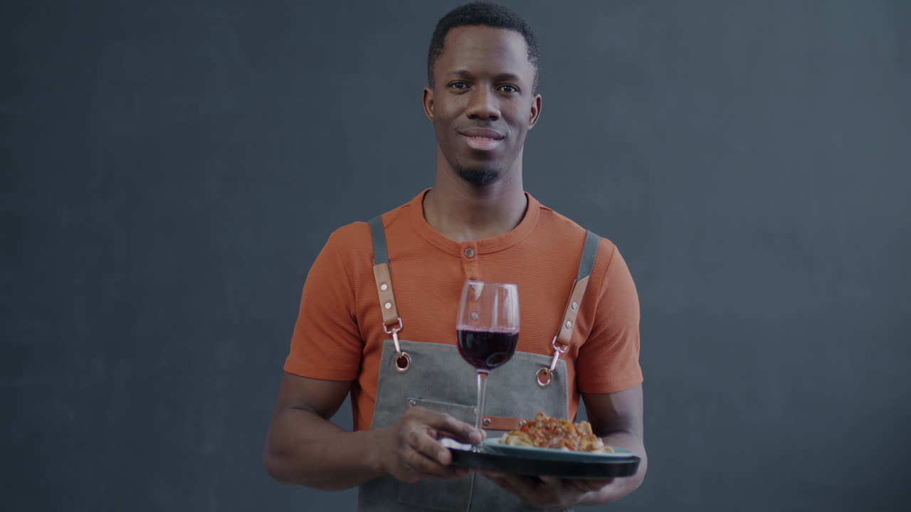 Smiling waiter serving food and wine