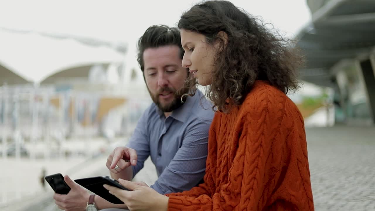 pareja que usa dispositivos digitales al aire libre