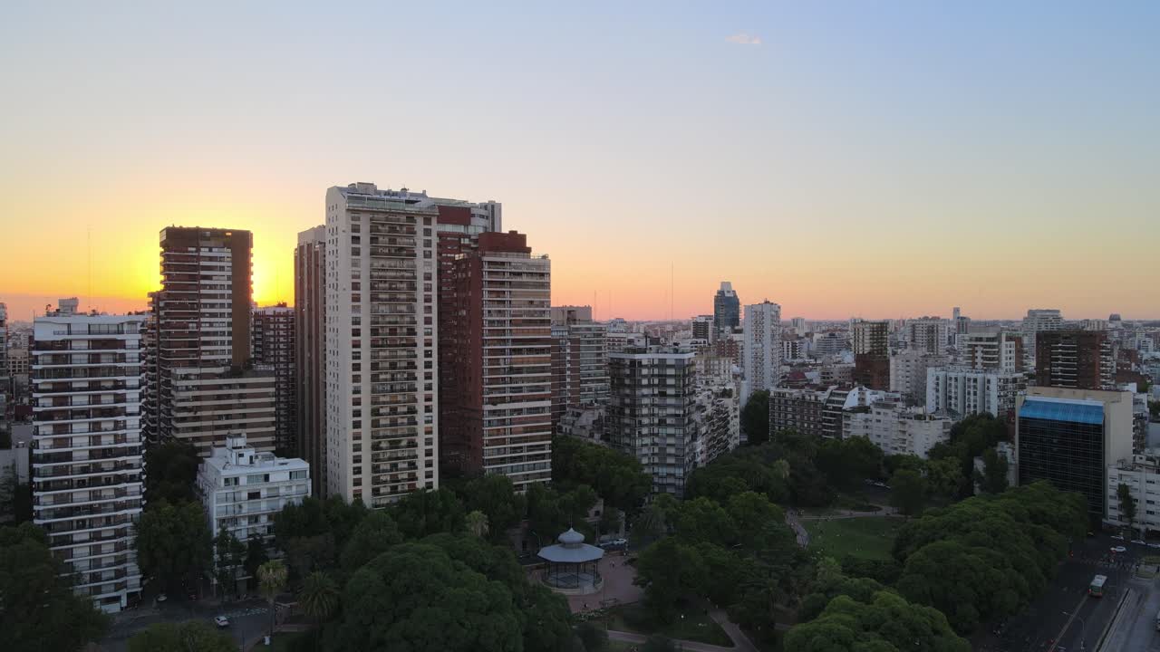 jib up volando sobre el parque barrancas de belgrano revelando edificios altos y la puesta de sol en el fondo, buenos aires, argentina