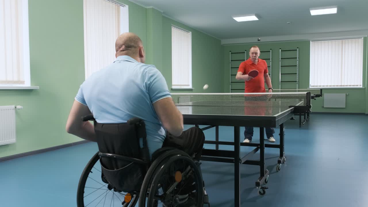체어에 앉아 있는 남자가 핑핑을 하고, 장애인들이 탁구를 하고, 장애인의 재활, 패럴림픽 스포츠.