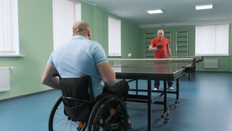 un hombre en silla de ruedas juega ping pong. personas con discapacidad juegan tenis de mesa. rehabilitación de discapacitados. deporte paralímpico.
