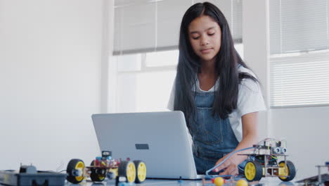 female student building and programing robot vehicle in after school computer coding class