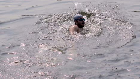 indian man swimmer swimming in river open water with swimming cap and goggles